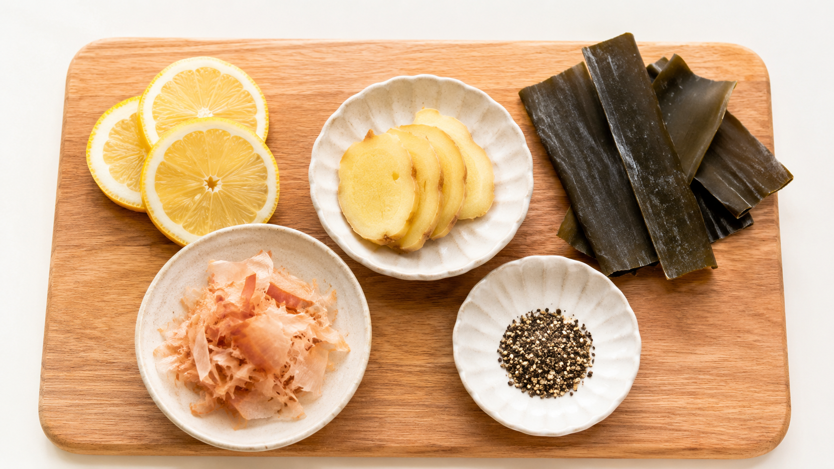 まな板の上のスライスしたレモンとしょうが、昆布、かつお節——塩に頼らず酸味と香り、うま味で味を出す減塩調理のイメージ
