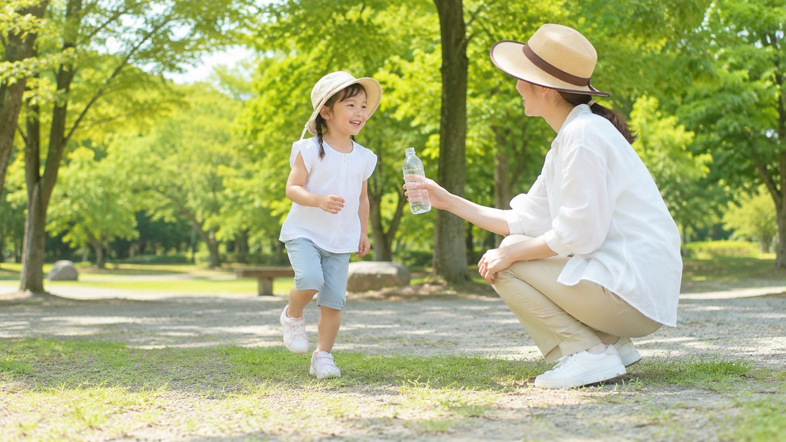 夏の公園で、日よけ帽子をかぶった元気な子どもを見守り、水分をすすめる親のイメージ。子どもの熱中症は大人の見守りと水分補給が大切